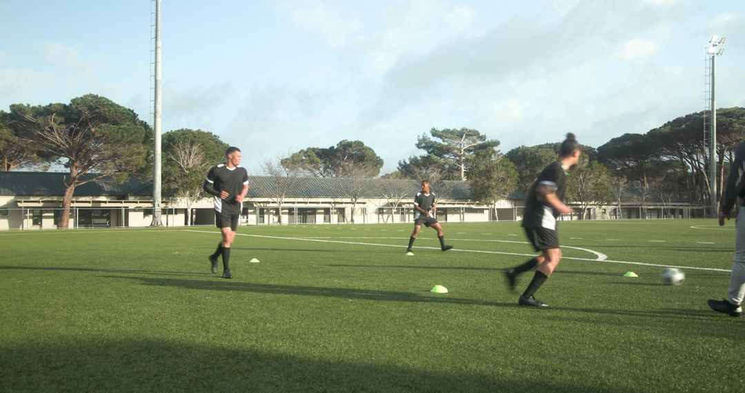Competitive Soccer Players Practicing with Cones on Green Field