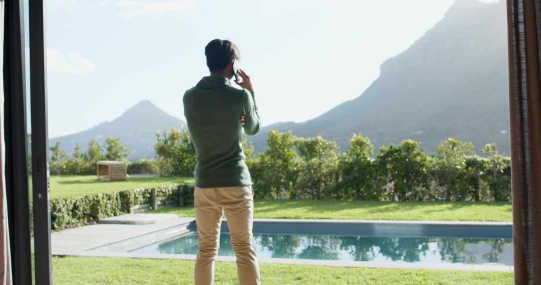 Man Overlooking Pool While on Phone in Modern Home with Mountain View