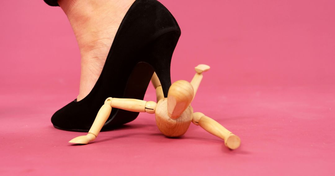 Wooden Figure Trapped Under High Heel Against Pink Background - Free Images, Stock Photos and Pictures on Pikwizard.com