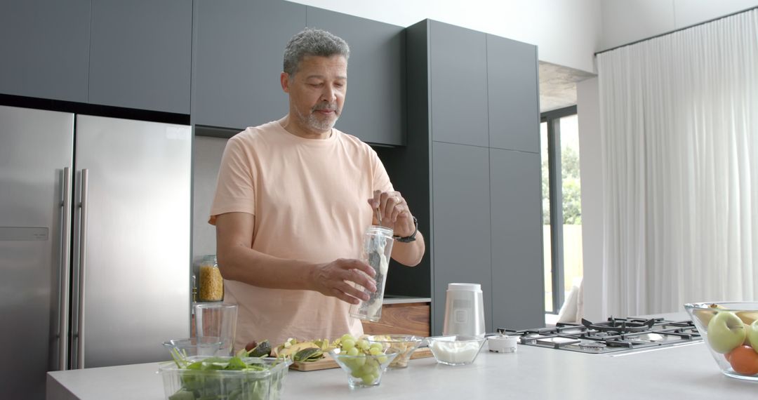 Middle-aged man preparing healthy smoothie in modern kitchen - Free Images, Stock Photos and Pictures on Pikwizard.com