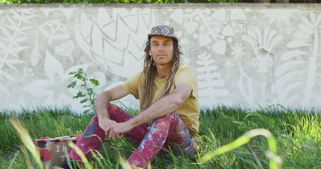 Artist with Dreadlocks Sitting in Garden, Wearing Paint-Splattered Clothes - Free Images, Stock Photos and Pictures on Pikwizard.com