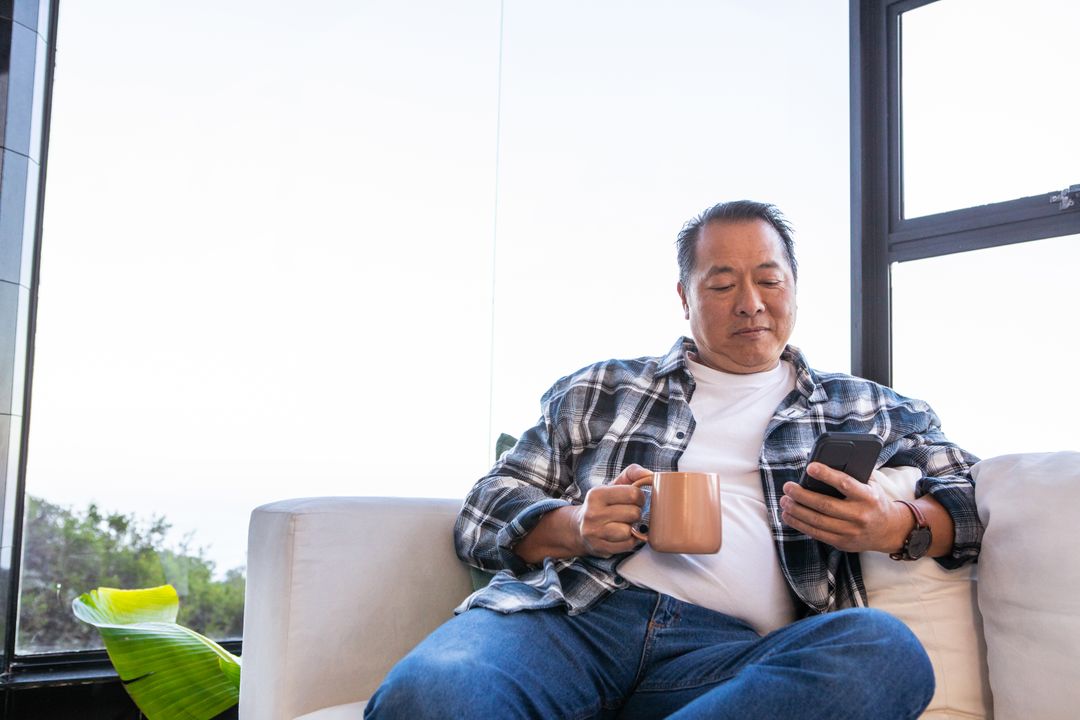 Relaxed Man Enjoying Morning Routine with Coffee and Smartphone