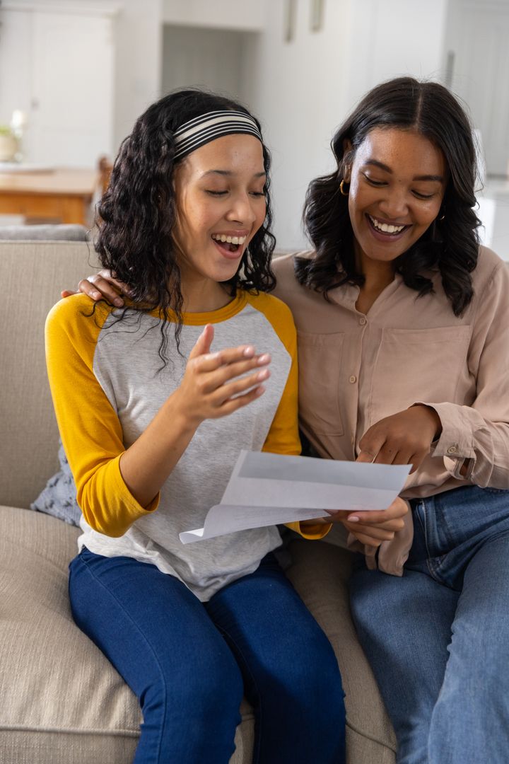 Mother Discussing Documents with Joyful Teen Daughter at Home