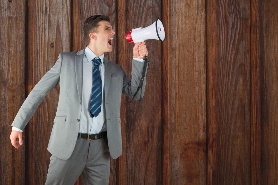 Businessman shouting on megaphone against wooden wall - Free Images, Stock Photos and Pictures on Pikwizard.com