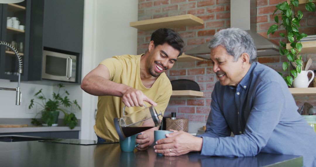 Young man pouring coffee for smiling older man at kitchen counter - Free Images, Stock Photos and Pictures on Pikwizard.com