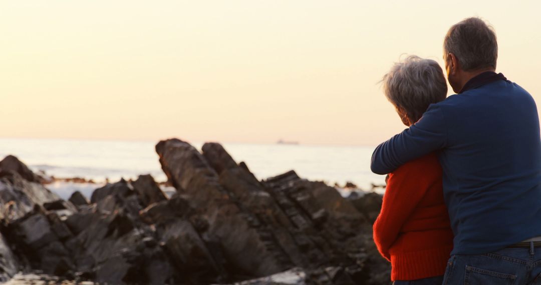 Elderly Couple Embracing by Coastal Sunset - Free Images, Stock Photos and Pictures on Pikwizard.com