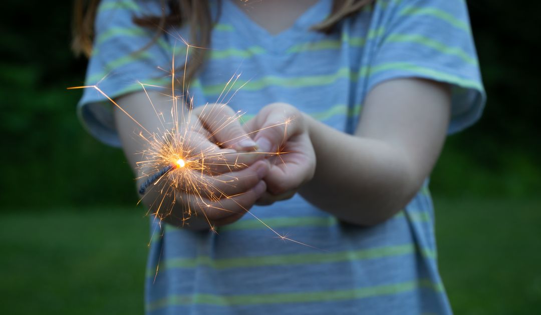 Child Holding Sparkler Sparks in Hands with a Focus on Shimmer