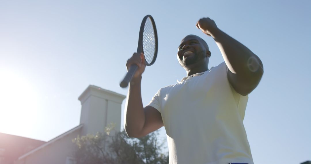 Athlete Celebrating Win with Tennis Racket under Clear Sky