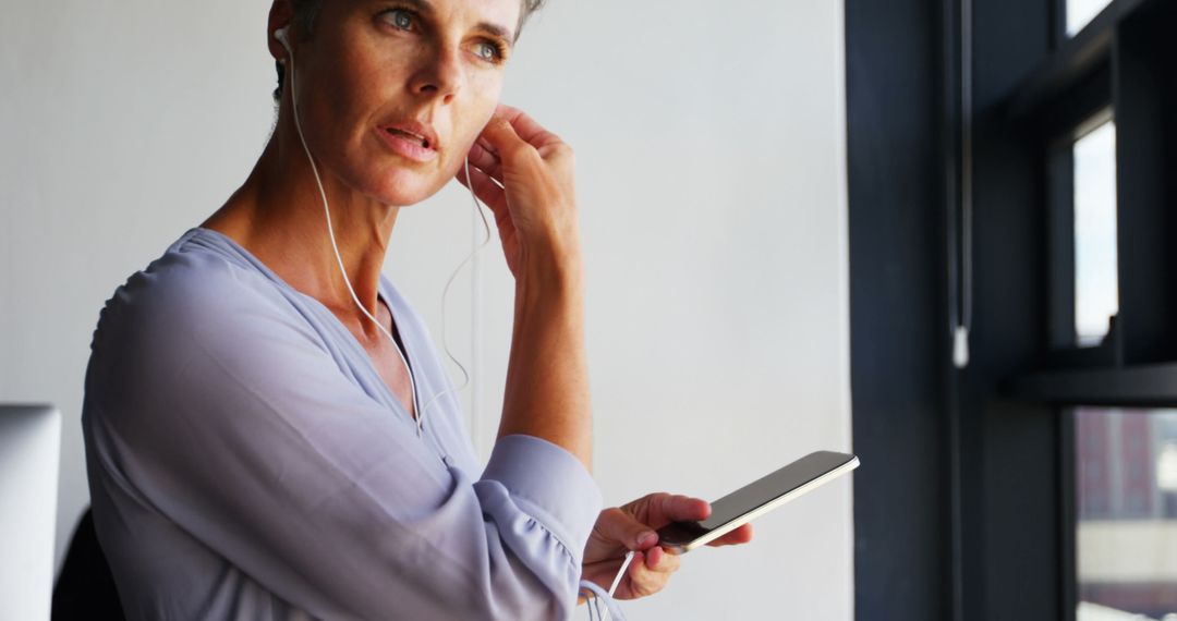 Woman Listening to Music with Earphones and Holding Smartphone - Free Images, Stock Photos and Pictures on Pikwizard.com