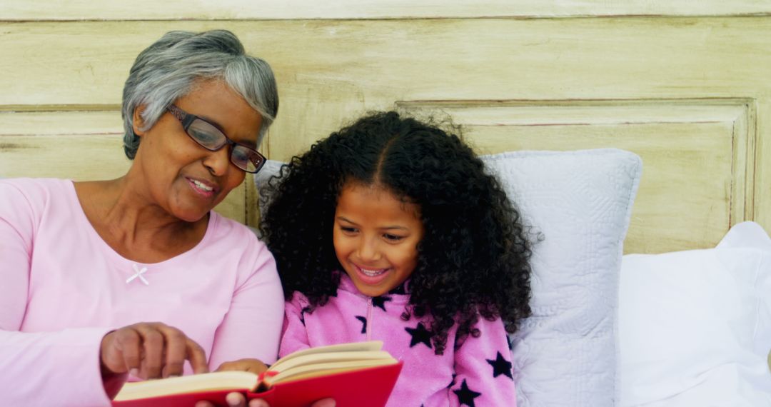 Grandmother Reading Book to Smiling Granddaughter in Bed - Free Images, Stock Photos and Pictures on Pikwizard.com