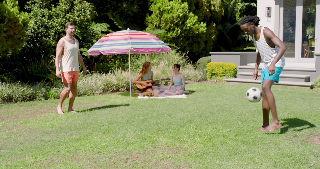 Diverse Friends Relaxing in Sunny Backyard with Guitar Playing