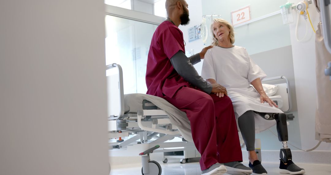 Nurse comforting elderly woman with prosthetic leg in hospital ward - Free Images, Stock Photos and Pictures on Pikwizard.com