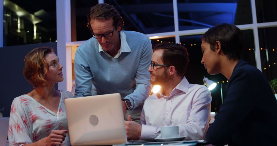 Diverse Professionals Collaborating in Night Office Setting with Laptop