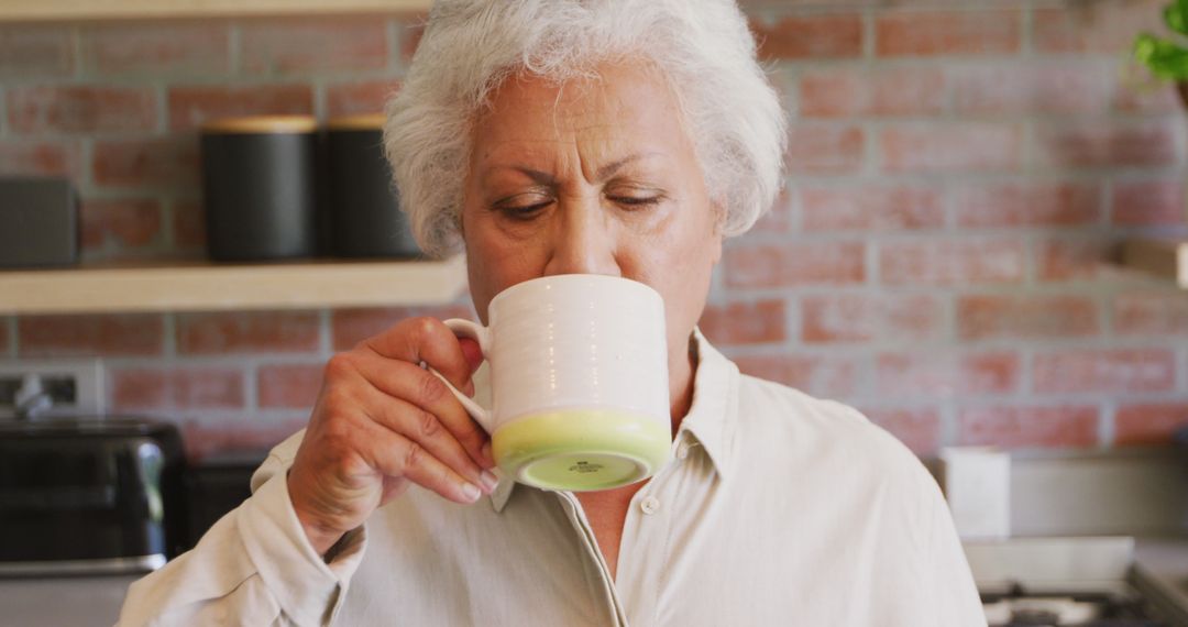 Senior Woman Enjoying Hot Beverage in Modern Kitchen - Free Images, Stock Photos and Pictures on Pikwizard.com