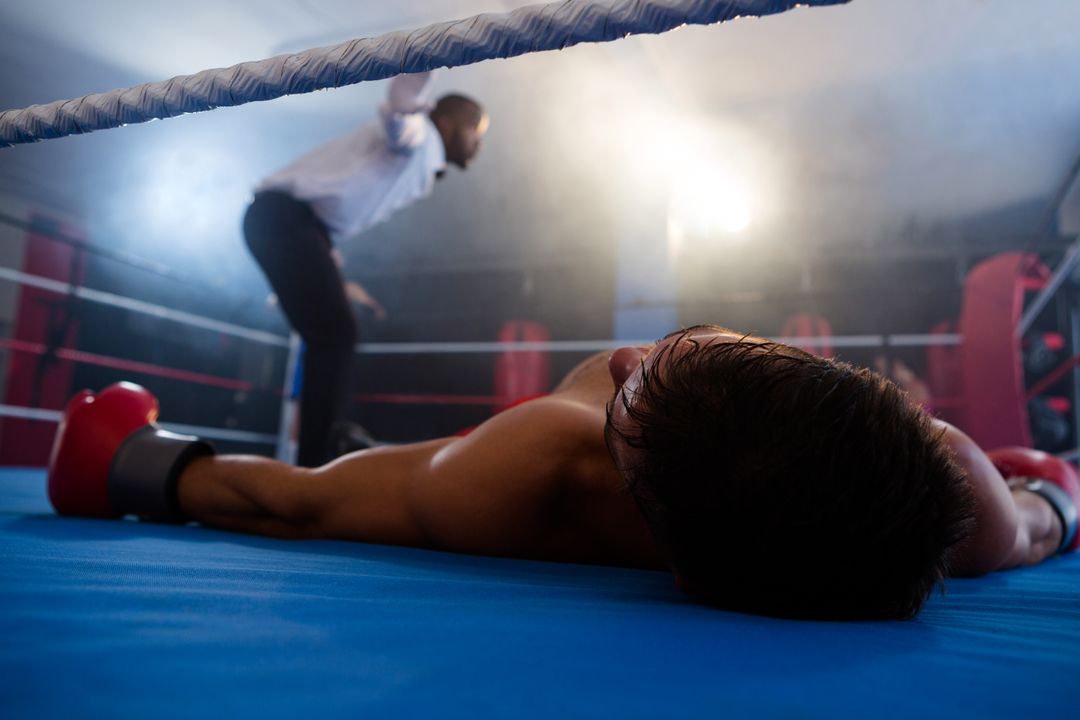 Unconscious boxer lying by referee in ring - Free Images, Stock Photos and Pictures on Pikwizard.com