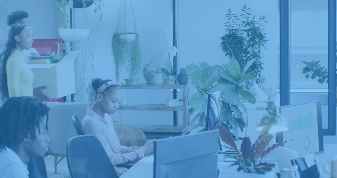 Young professionals typing and collaborating in bright plant-filled open-plan workspace