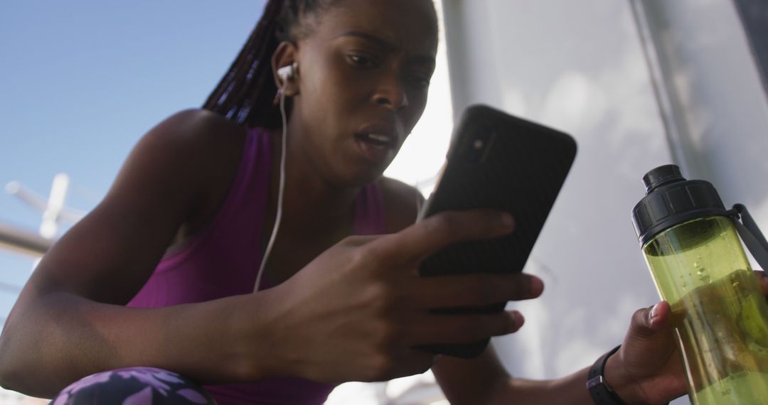 Focused woman checking smartphone during workout outdoors - Free Images, Stock Photos and Pictures on Pikwizard.com