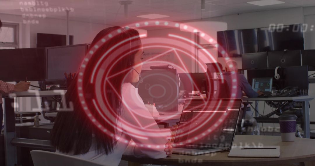 Professional woman working on laptop with red digital HUD overlay in modern open office