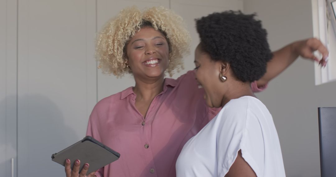 Two Caucasian Women Sharing Laughter Over Tablet in Modern Home