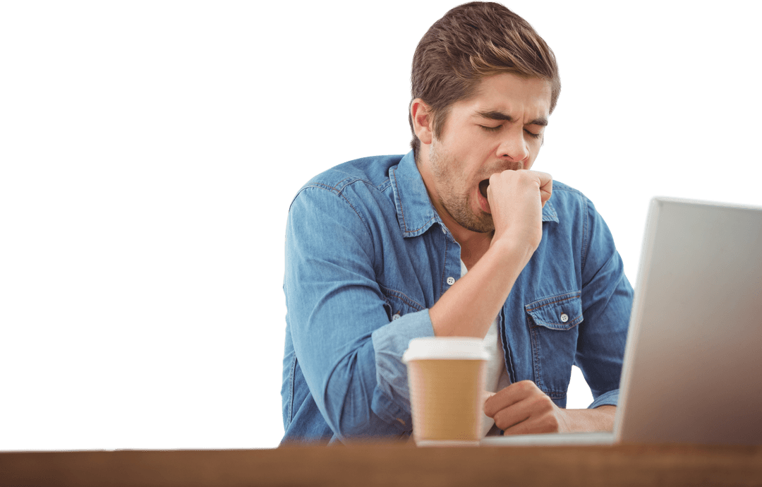 Tired Professional Yawning at Desk with Coffee and Laptop