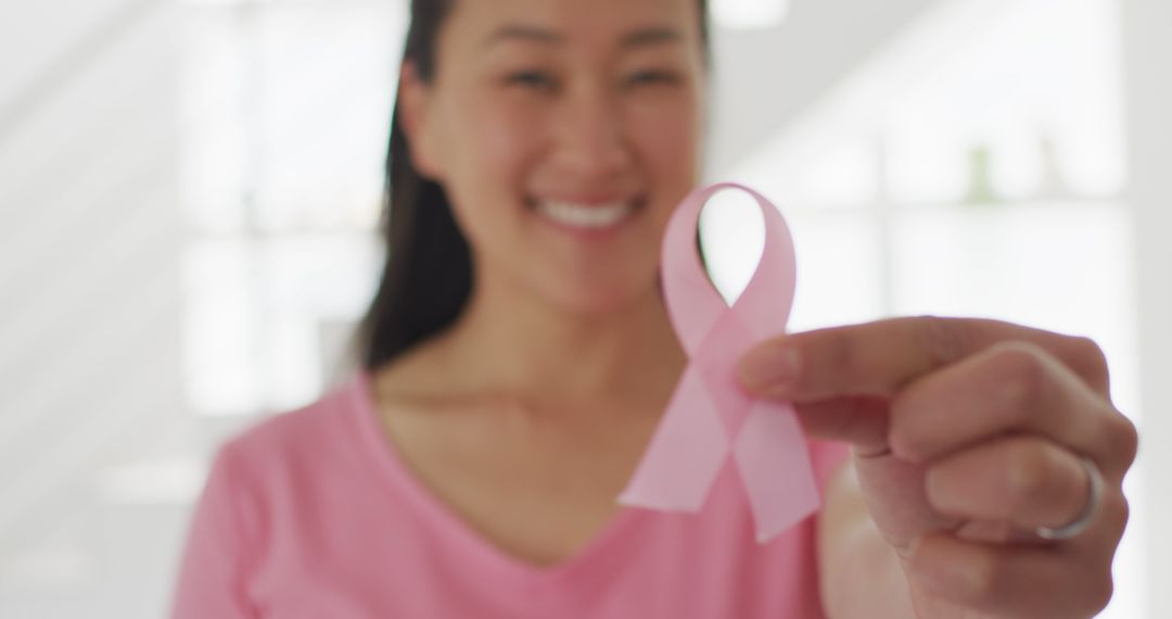 Smiling Woman Holding Pink Ribbon Symbolizing Breast Cancer Awareness - Free Images, Stock Photos and Pictures on Pikwizard.com