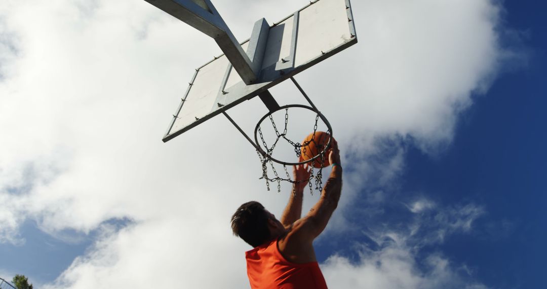 Young Man Dunks Basketball on Outdoor Hoop Against Blue Sky - Free Images, Stock Photos and Pictures on Pikwizard.com