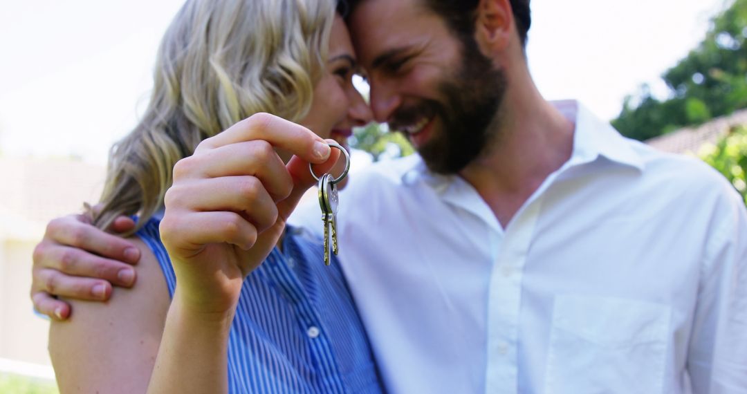 Happy Couple Celebrating New Home with Keys on Sunny Day