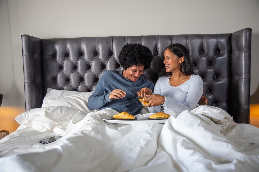 Happy Couple Enjoying Breakfast in Bed with Croissants and Juice