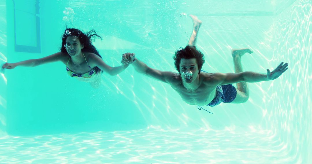 Couple Swimming Underwater Holding Hands Enthusiastically
