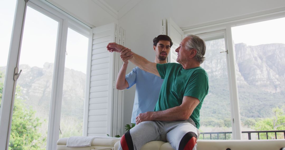 Physical Therapist Assisting Senior Man with Arm Exercises in Sunny Room - Free Images, Stock Photos and Pictures on Pikwizard.com