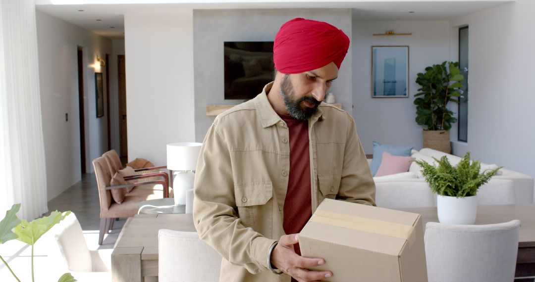 Man in Red Turban Moving Cardboard Box in Modern Living Room