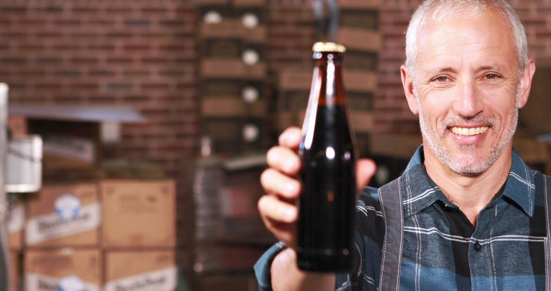 Brewery Worker Displaying Beer Bottle in Warehouse - Free Images, Stock Photos and Pictures on Pikwizard.com