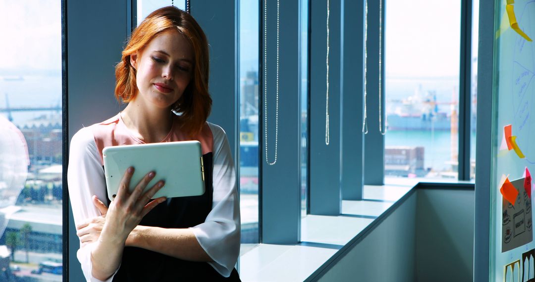 Businesswoman Reading Digital Tablet at Office Window - Free Images, Stock Photos and Pictures on Pikwizard.com