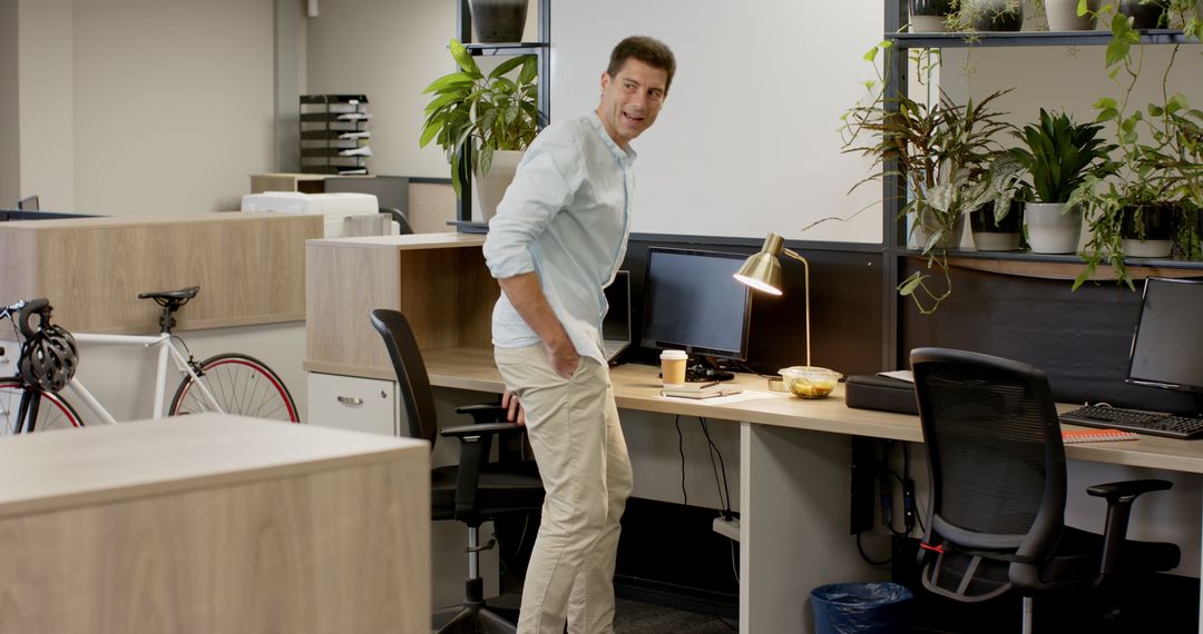 Man Adjusting Shirt in Contemporary Office with Large Desktop Setup