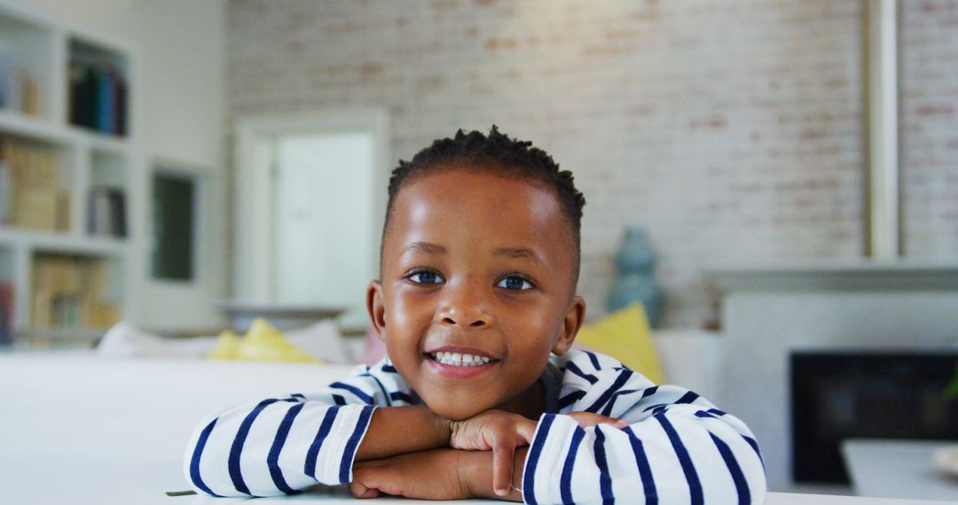 Smiling African American Child Relaxing at Home in Striped Shirt - Free Images, Stock Photos and Pictures on Pikwizard.com