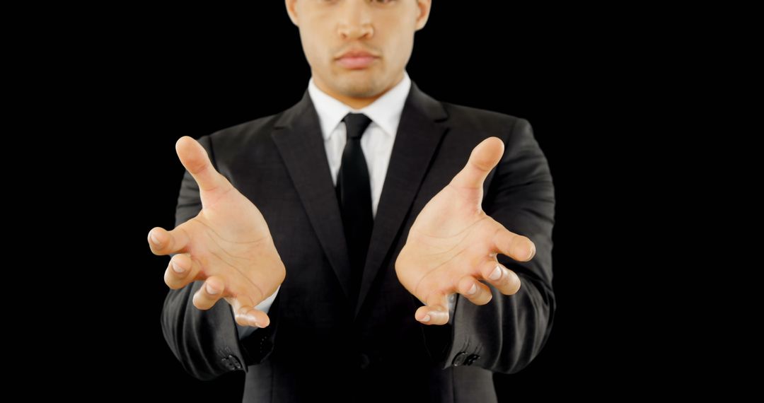 Businessman Holding Invisible Object Against Dark Background
