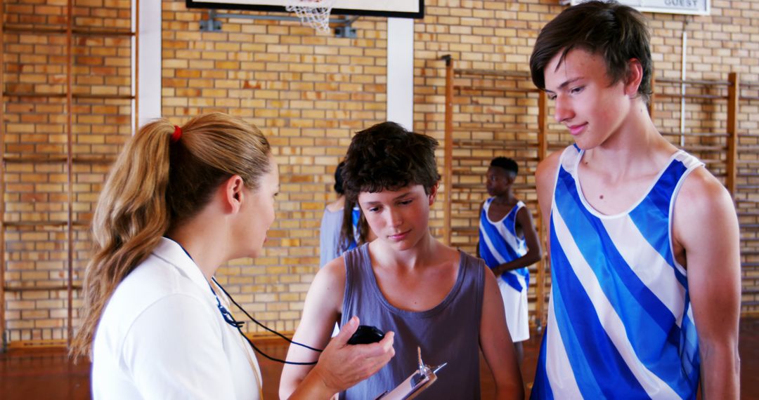 Sports Coach Checking Pulse of Two Teenage Boys at School Gym - Free Images, Stock Photos and Pictures on Pikwizard.com