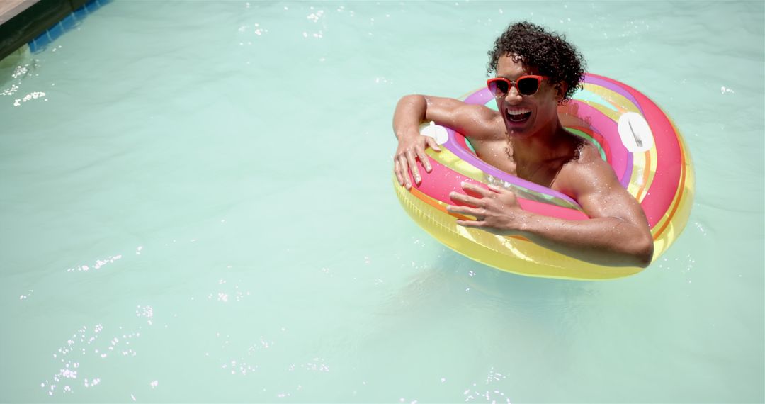 Man Relaxing in Pool with Colorful Inflatable Ring on Sunny Day