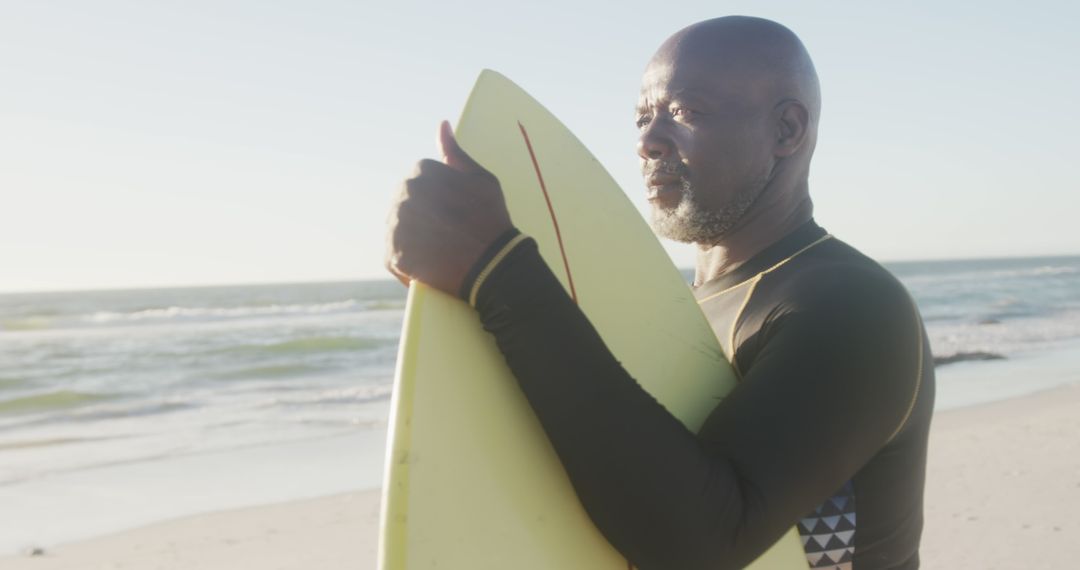 Elderly Man Holding Surfboard at Beach During Sunset - Free Images, Stock Photos and Pictures on Pikwizard.com