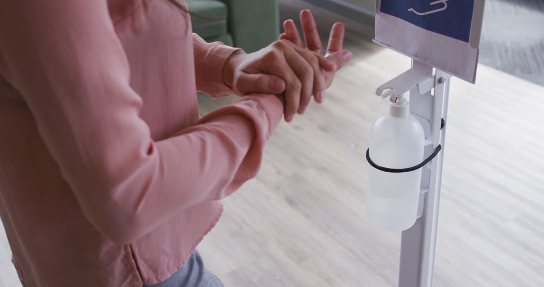 Person in Pink Top Using Hand Sanitizer in Modern Indoor Space - Free Images, Stock Photos and Pictures on Pikwizard.com