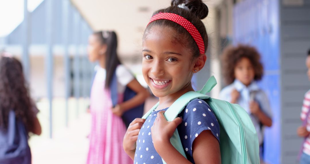Smiling Girl with Backpack in School Hallway with Classmates