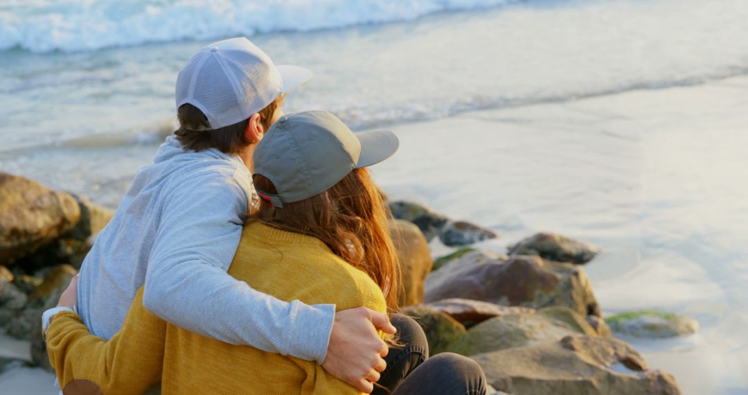 Young Couple Embracing by the Seaside Watching Waves in Tranquil Moment - Free Images, Stock Photos and Pictures on Pikwizard.com