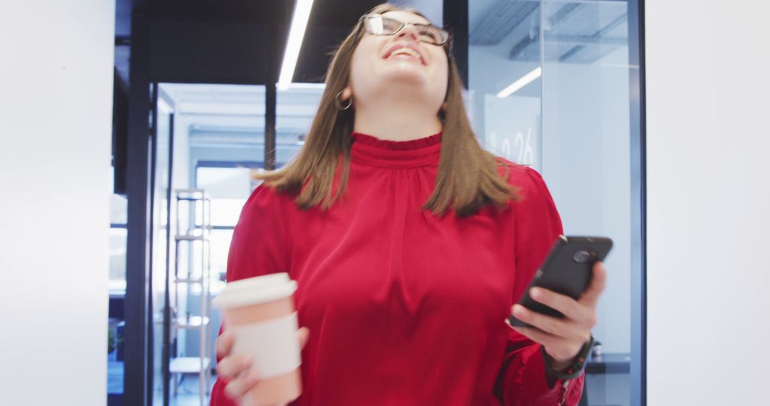 Excited Businesswoman Holding Coffee and Smartphone in Modern Office - Free Images, Stock Photos and Pictures on Pikwizard.com