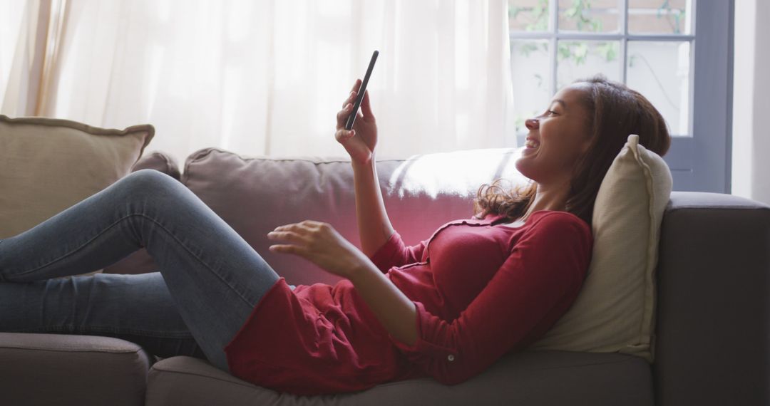 Young Woman Relaxing on Sofa and Browsing Smartphone in Cozy Living Room - Free Images, Stock Photos and Pictures on Pikwizard.com