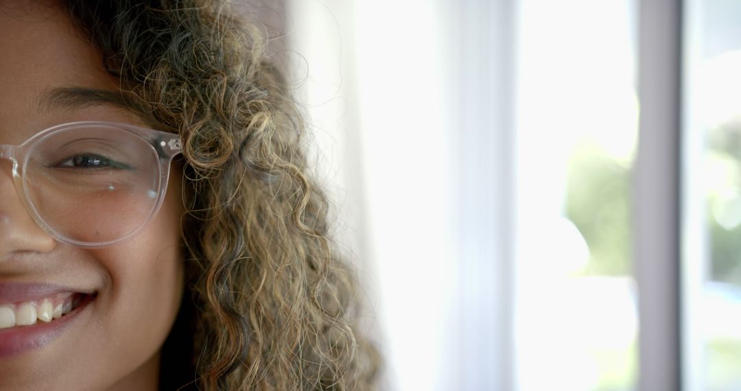 Close-up of Smiling Woman with Curly Hair and Glasses in Bright Room - Free Images, Stock Photos and Pictures on Pikwizard.com