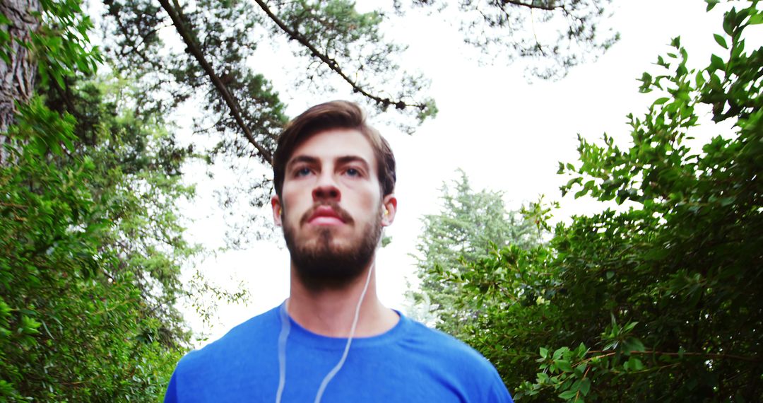 Young Man Jogging Outdoors with Headphones in Forest - Free Images, Stock Photos and Pictures on Pikwizard.com