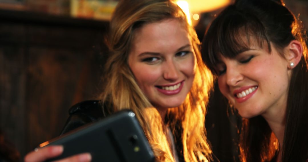 Women Smiling while Taking Selfie Together at Evening Social Event - Free Images, Stock Photos and Pictures on Pikwizard.com