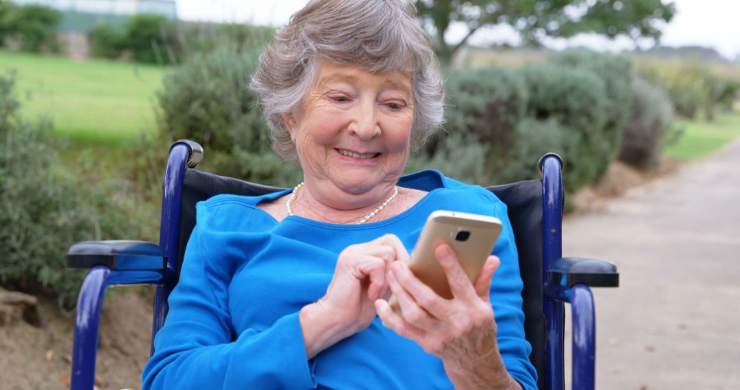 Senior Woman in Blue Shirt Using Smartphone Outdoors - Free Images, Stock Photos and Pictures on Pikwizard.com