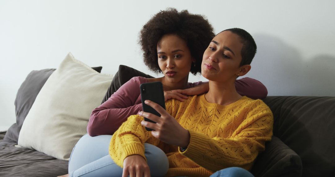 Mixed Couple Relaxing on Couch with Smartphone; Enjoying Cozy Time
