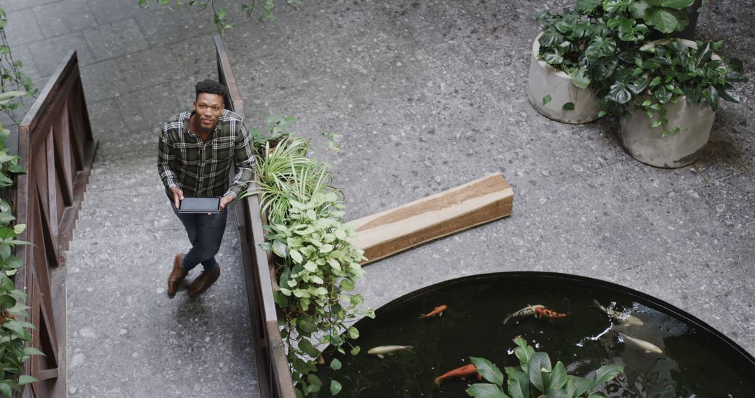 Man Observing Indoor Pond with Fish and Greenery - Free Images, Stock Photos and Pictures on Pikwizard.com